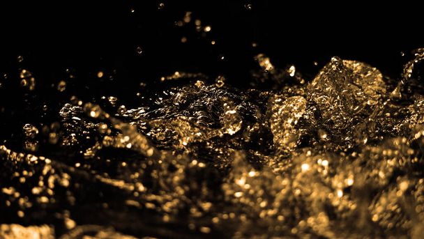 Hochgeschwindigkeits-Nahaufnahmen von Ölflüssigkeit aus Dieselkraftstoff, die spritzt und sich auf schwarzem Hintergrund in die Luft bewegt. Kraft der Brennstoffflüssigkeit, die aktiv und leistungsstark ist. Studio Shot Premium Gold Farbton - Foto, Bild