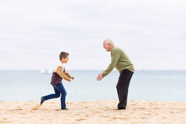幸せな少年は浜で彼の祖父を抱擁するために走っている - 写真・画像