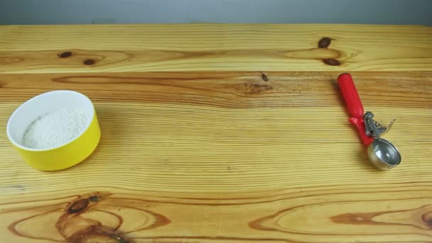 bovenaanzicht aan lege houten tafel met metalen lepel en kom met kokosvlokken - Video
