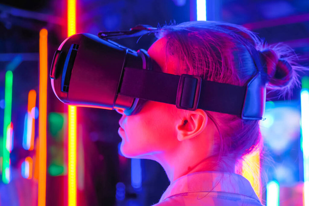 Vue latérale : une femme utilise un casque de réalité virtuelle lors d'une exposition interactive VR - Photo, image