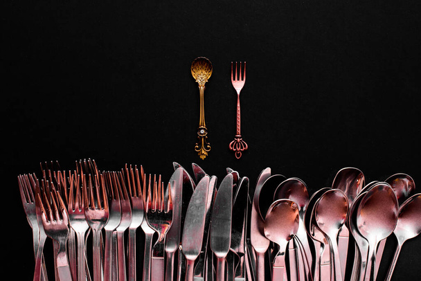 A luxury golden spoon stands out from the rest of the simpler and cheaper cutlery, isolated on a black background with copy space. - Photo, Image
