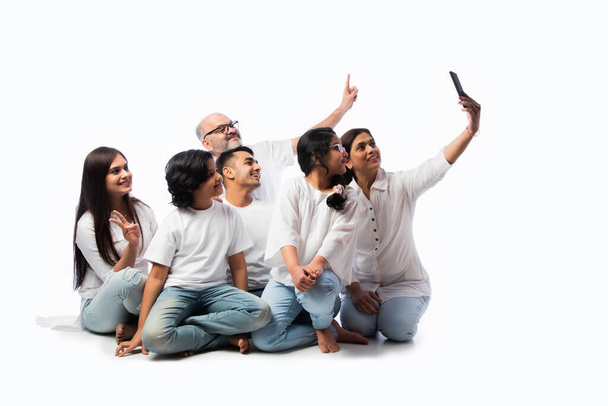 Famille indienne de six appels vidéo sur smartphone ou de prendre des photos selfie contre blanc - Photo, image