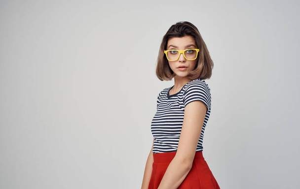 portrait of a woman with glasses and a striped t-shirt on a gray background fashion style red skirt - Photo, Image