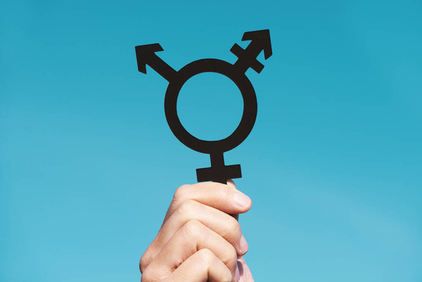close-up van een jonge blanke persoon met een transgender symbool tegen de blauwe lucht - Foto, afbeelding
