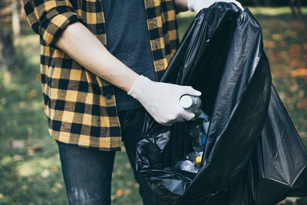 Vapaaehtoisilla miehillä on vesipulloja tai muovipusseja, jotka ovat pudonneet puistoon, laita ne roskakoriin, ympäristönsuojelu tai vapaaehtoistyö hyväntekeväisyyteen, jätehuolto kierrättämällä. - Valokuva, kuva