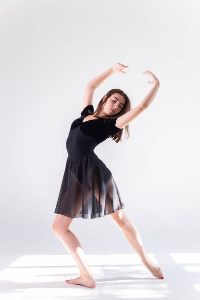 Sportswoman in black sports dress on a white isolated background with place for text or logo. The dancing girl on a white background. - Photo, Image