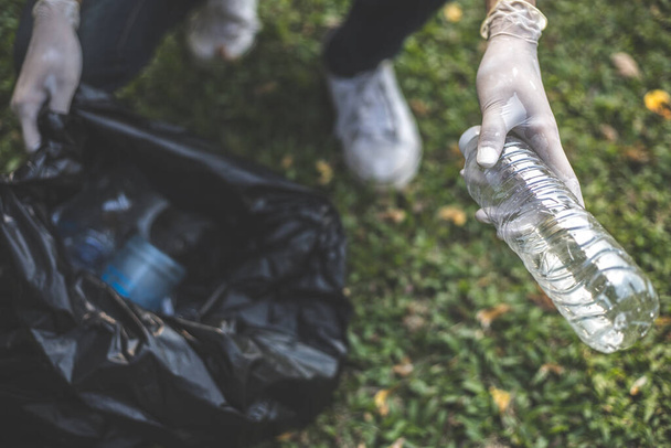 Voluntarios masculinos llevan botellas de agua o bolsas de plástico que han caído en el parque los ponen en botes de basura, Protección del medio ambiente o voluntariado para caridad, Eliminación de residuos a través del reciclaje. - Foto, Imagen
