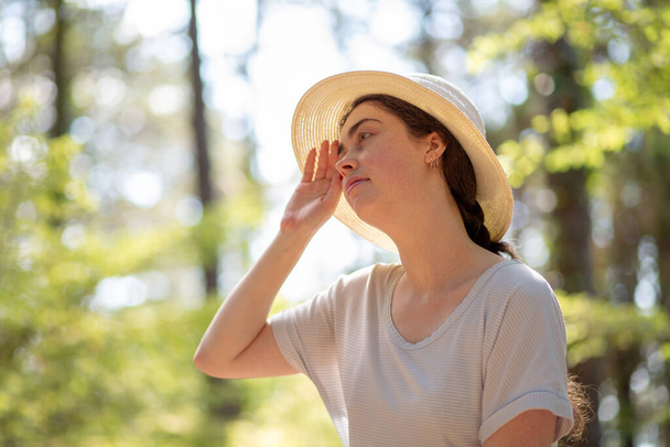 Retrato de uma jovem cansada com um chapéu de palha, limpando o suor da testa. Verão e quente. O conceito de proteção contra insolação. - Foto, Imagem