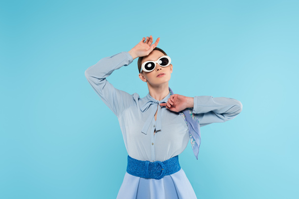 trendi nő napszemüvegben pózol a kezét közel arc elszigetelt kék - Fotó, kép