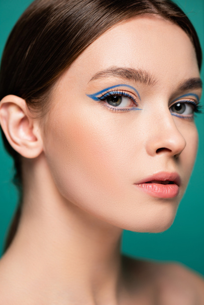 close-up portret van mooie jonge vrouw met blauwe eyeliner geïsoleerd op groen - Foto, afbeelding