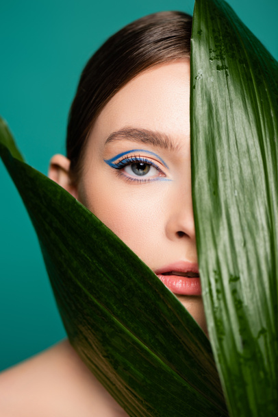 sensual woman looking at camera near glossy leaves isolated on green - Foto, immagini