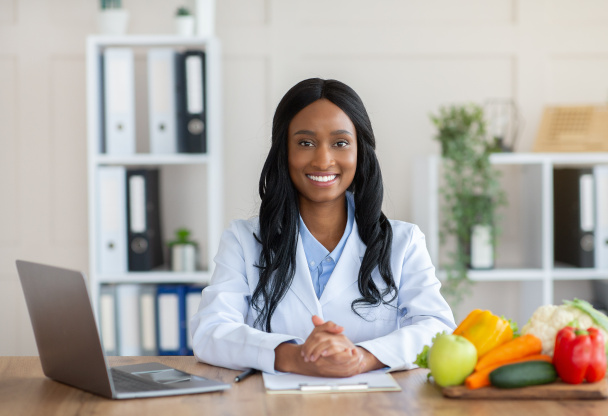 Comida inteligente y nutrición saludable. Retrato del dietista negro positivo mirando a la cámara y sonriendo en el lugar de trabajo - Foto, imagen