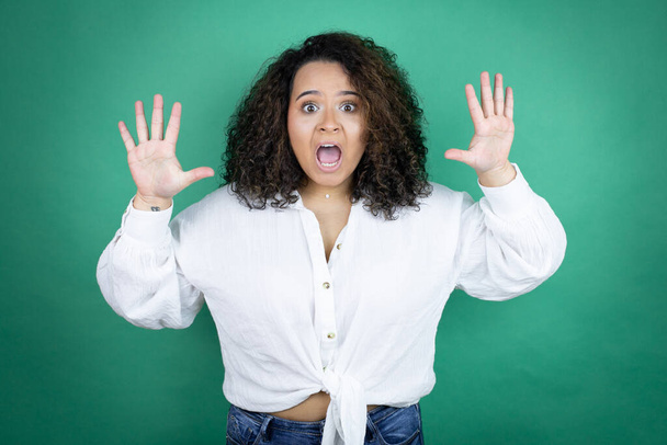 Young african american girl wearing white shirt over green background showing and pointing up with fingers number ten while smiling confident and happy - Photo, Image