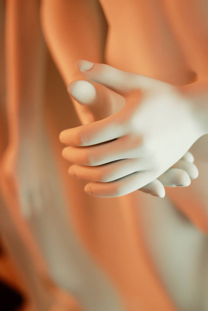 κάθετη φωτογραφία των χεριών μιας λευκής μανεκέν με πορτοκαλί φώτα - Φωτογραφία, εικόνα