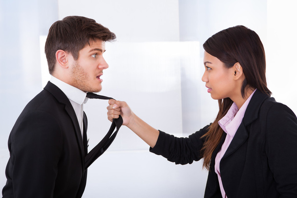 femme d'affaires en colère tenant la cravate d'homme d'affaires - Photo, image
