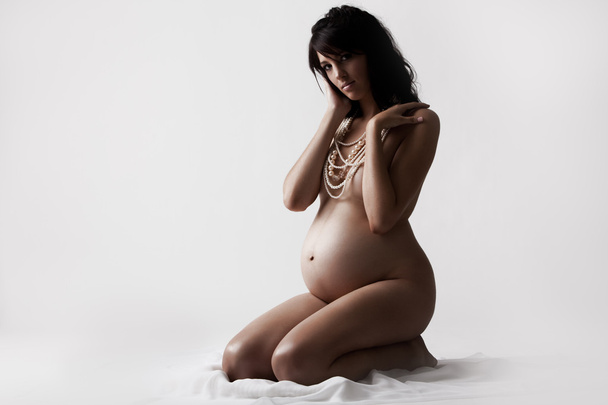 地面に座っている若い裸の妊娠中の女性 - 写真・画像