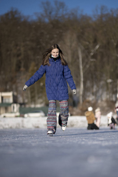 冬のアイススケート女の子持っています楽しいですオンアイススケートリンク屋外.  - 写真・画像