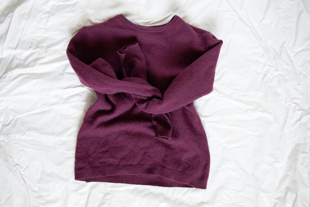 suéter de lana roja de las mujeres se encuentra en un fondo de luz arrugada - Foto, Imagen