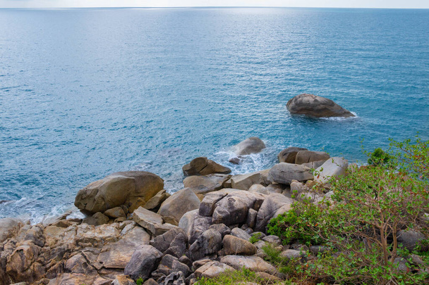 崖から海の岩へのトップビューとタイのサムイ島の波でサーフィン。岩の多い海岸に対する美しい青い波 - 写真・画像