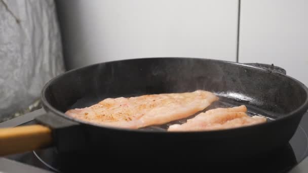 Chicken fillet is frying on grill pan at kitchen restaurant. Delicious slices of meat is roasting on a hot skillet at cuisine. Process of making tasty dish. Concept of preparing food. Dolly shot - Footage, Video