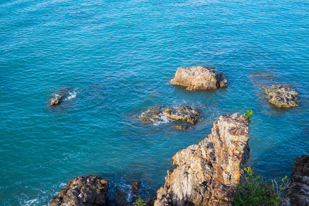 Top uitzicht vanaf de klif op de zee rotsen en surfen met golven. Mooie blauwe water golven tegen rotsachtige kust - Foto, afbeelding