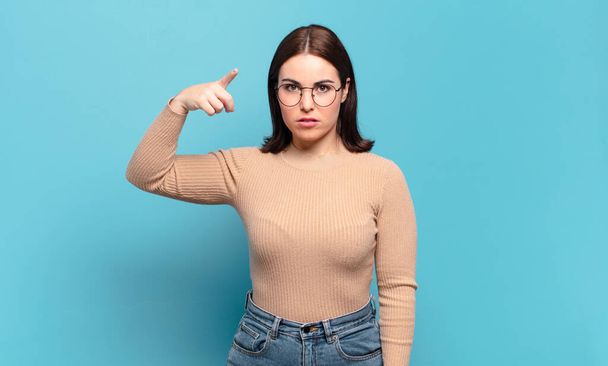 young pretty casual woman pointing at camera with an angry aggressive expression looking like a furious, crazy boss - Photo, image