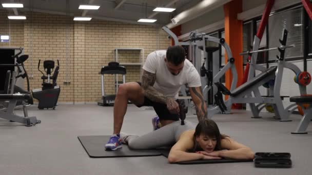 Entrenador personal con pistola de masaje en el cuerpo de la deportista - Imágenes, Vídeo