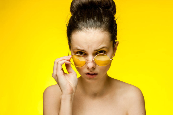 ładna kobieta z gołymi ramionami żółte okulary emocje przycięte widok - Zdjęcie, obraz