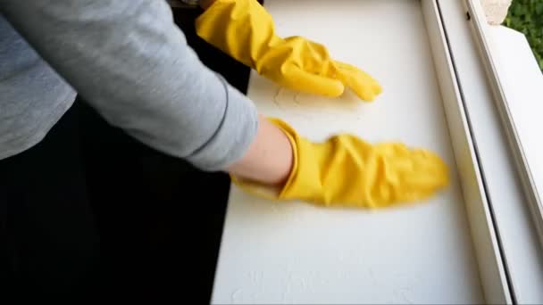 Mano de mujer en guantes amarillos lavando alféizar de ventana. Servicios de limpieza de ventanas concepto. - Metraje, vídeo