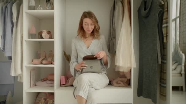 Stilvolle junge Mutter zeigt Parfüm neugierigen Tochter sitzt auf Kleiderschrank Regal mit Kleidung in der Umkleidekabine. 4K-Video - Filmmaterial, Video