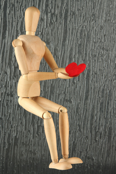 Wooden mannequin holding red heart on gray background - Foto, Imagem