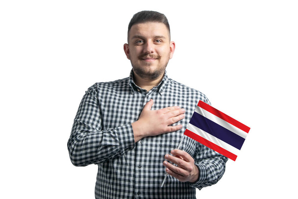 Chico blanco sosteniendo una bandera de Tailandia y sostiene su mano sobre su corazón aislado sobre un fondo blanco Con amor a Tailandia. - Foto, imagen
