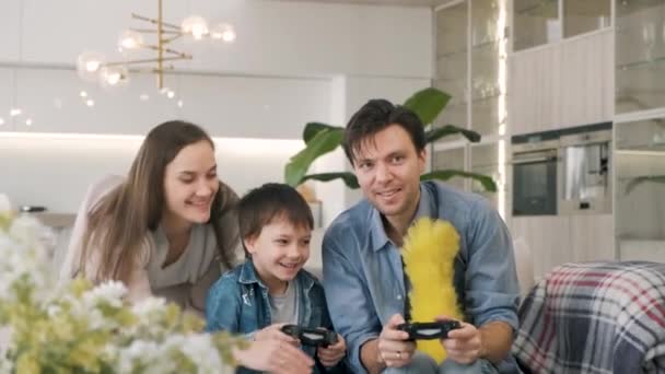 Familia joven divirtiéndose en casa. Padre e hijo jugando videojuego - Imágenes, Vídeo