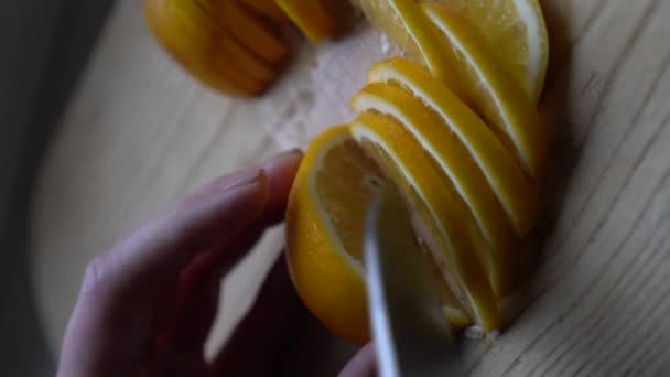 Γυναίκα με ένα μεγάλο κοφτερό μαχαίρι κόβει ένα λεμόνι σε έναν πίνακα κουζίνας για μαγείρεμα τροφίμων και ποτών. Η υφή είναι ζουμερές φέτες από lime φρούτα closeup. Flu θεραπεία έννοιες Κάθετη βίντεο. Επιλεκτική εστίαση - Πλάνα, βίντεο