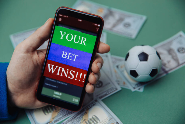 Males hand holds smartphone with bet application. Victory message. Gambling and bet concept - Photo, Image