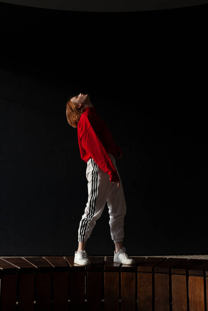 a girl in a tracksuit warms up before running on the street on a sunny day - Foto, immagini