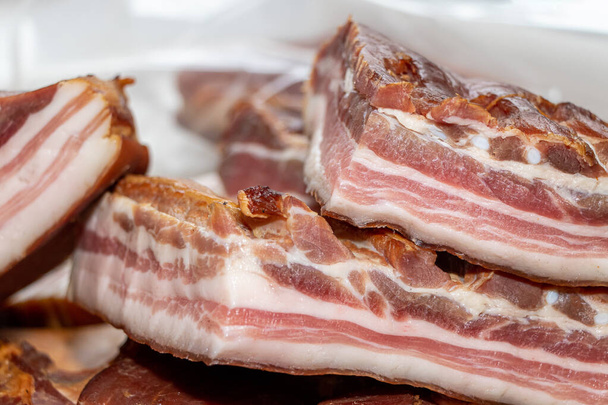 bacon de porc fumé sur une planche de bois avec plusieurs morceaux coupés - Photo, image