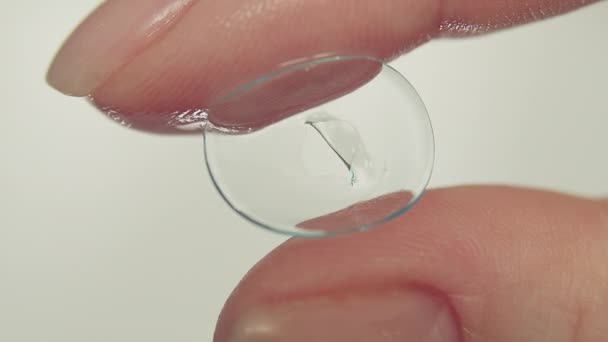 Dedos femeninos sosteniendo lente de contacto suave dañada, primer plano - Metraje, vídeo