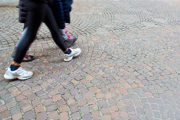 Mensen lopen in een voetgangerszone geplaveid met kleine stenen. - Foto, afbeelding