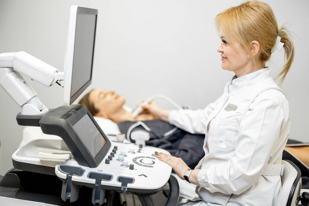 診療所で超音波検査を受けた女性患者の甲状腺検査医師 - 写真・画像