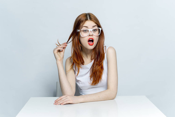 woman in white dress sitting at the table wearing glasses red lips  - Foto, afbeelding