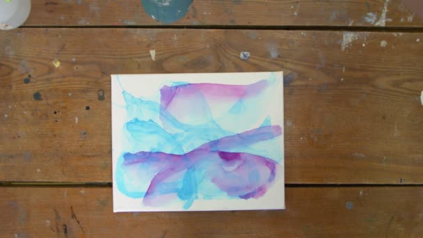 Nestetaidetta. Abstrakti sininen maalaus. Top näkymä naisartisti käyttää kuivausrumpu kuivua hänen uusi Fluid Art kuva sininen ja violetti värit - Materiaali, video