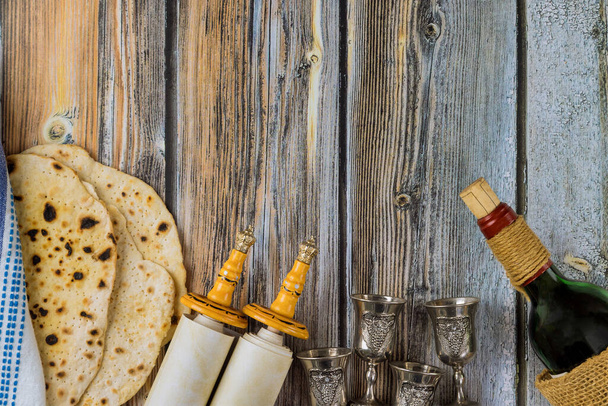 Passover celebrating of great Jewish family holiday symbols with kosher matzah traditional seder plate, torah scroll and four cup for wine - Photo, Image