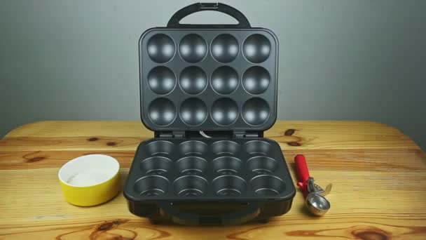 grande machine à cuire noire ouverte pour muffins faits servis sur table en bois jaune - Séquence, vidéo