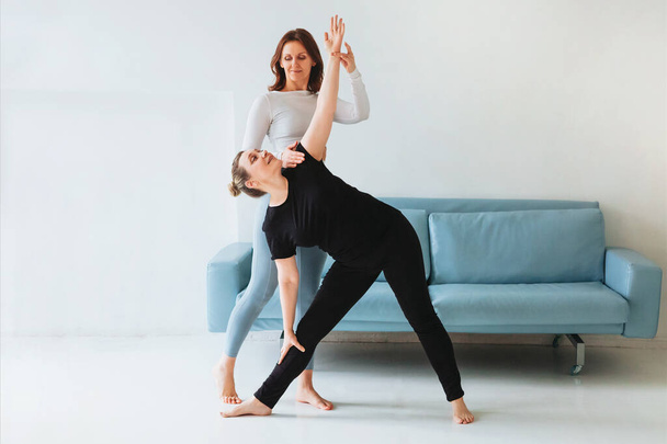 Femme adulte aidant la femme dans les vêtements de sport avec faire la pose de yoga et étirer les bras - Photo, image