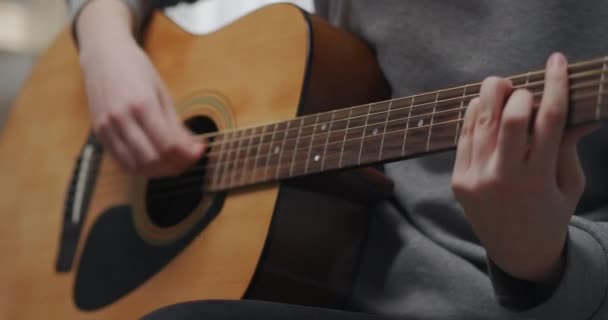 Egy tinédzser új akusztikus gitárakkordokat tanul otthon iskola után. Közelkép.. - Felvétel, videó