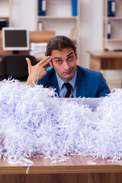 Genç bir erkek çalışan ve ofiste bir sürü kesik kağıt var. - Fotoğraf, Görsel