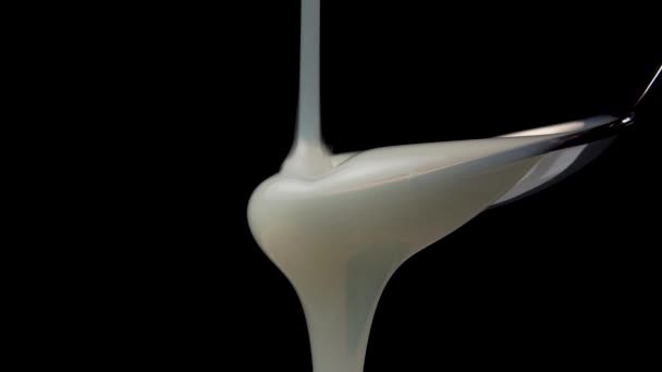 Creamy stream of dish washing detergent gel pours into a metal spoon in slow motion on a black background. Macro shot. Disinfection and sanitization concept - Materiał filmowy, wideo