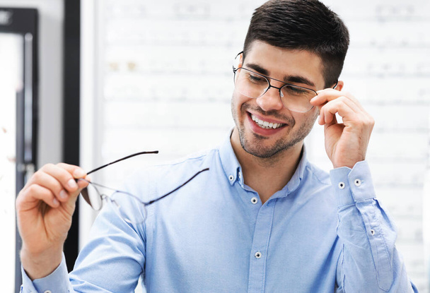 Retrato de feliz joven cliente masculino eligiendo gafas - Foto, imagen