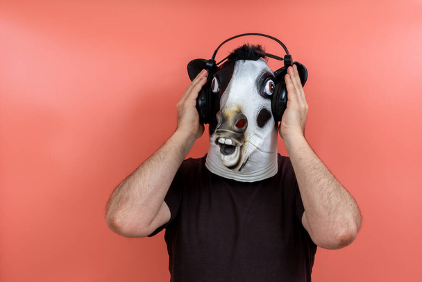 костюмований чоловік у коров'ячій масці слухає музику з навушниками з рожевим тлом
 - Фото, зображення